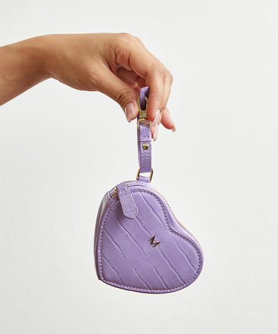 Women's hands holding heart shape coin box with strap in violet color
